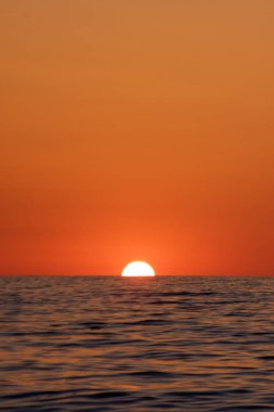 Deniz ve güneşin ufkun altında batışının dikey görüntüsü..