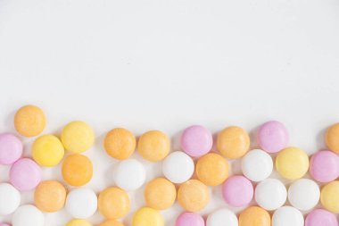 Beyaz arkaplanda düğme şeklindeki şekerlerin yakın plan görüntüsü.