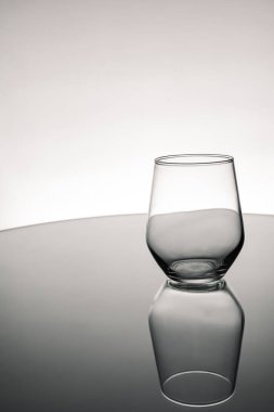 Masada yansıması olan gri ölçekli boş bir bardak.