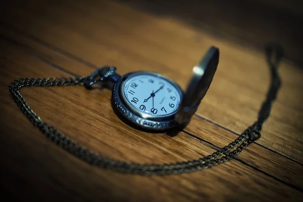An old antique quartz pocket watch on a wooden table.