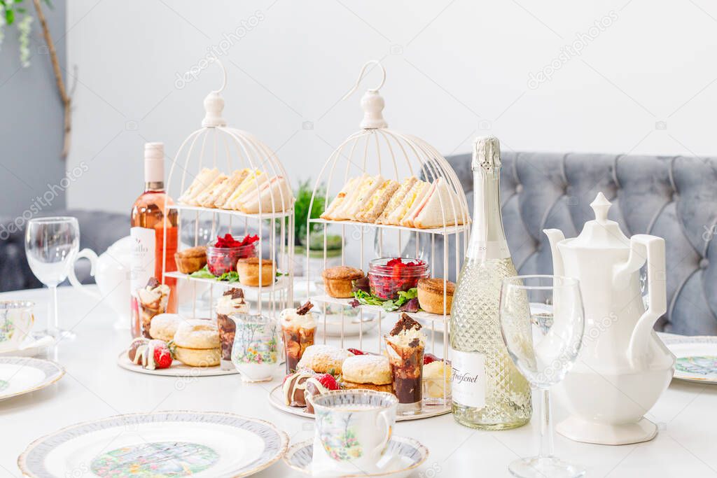 A celebratory afternoon tea table with scones, cakes and sandwiches alongside wine