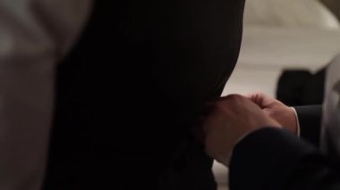 Bir arkadaş damadın düğün için giyinmesine yardım eder.