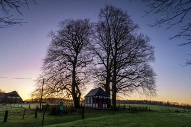 Gün doğarken ağaçların altında küçük bir şapel, Bergisch Gladbach, Almanya