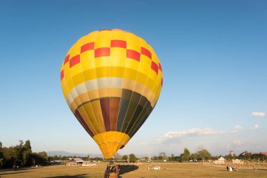 Renkli bir sıcak hava balonunun güzel bir görüntüsü üzerimizden uçuyor ve mavi bir gökyüzüne iniyor.