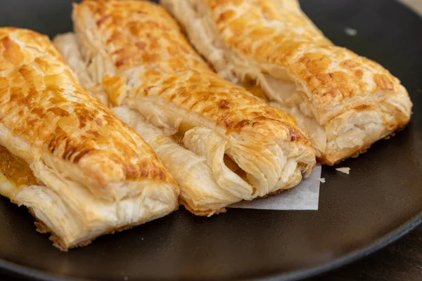 A baked puff pastry with toppings on a black plate