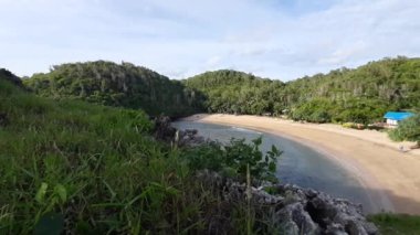Endonezya 'nın Java kentindeki dağlarla ve yağmur ormanlarıyla çevrili Pantai Kasap adlı göl kumsalındaki tepenin yüksek açılı görüntüsü..