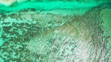 Güneşli bir günde, turkuaz bir denizin havadan görünüşü.