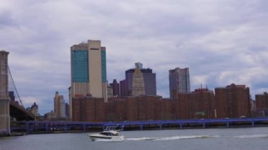 New York 'ta bulutlu bir günde bir köprünün altındaki bir nehirde giden beyaz bir motorlu teknenin güzel bir görüntüsü.