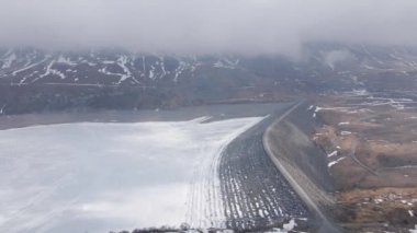 Mont Cenis (Moncenisio) 4K İHA. Dağlarda yolu olan donmuş göl ve barajın havadan görünüşü