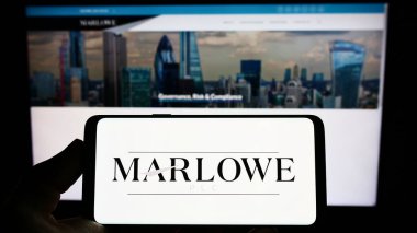 İngiliz uyum şirketi Marlowe plc 'un logosunun bulunduğu cep telefonu sahibi kişi iş sayfasının önünde ekranda. Telefon ekranına odaklan.