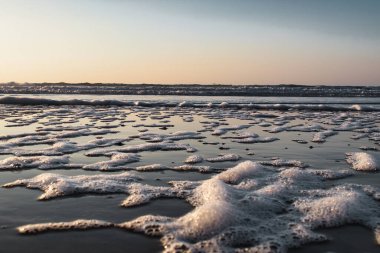 Büyüleyici bir günbatımı sırasında kıyıdan çekilen güzel bir denizin manzarası.