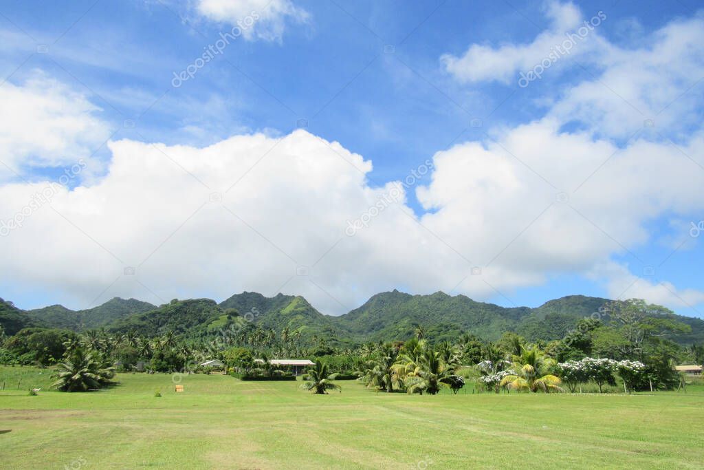 A view of Rarotonga's green tropical mountains with rainforests and a field in front