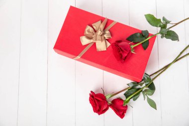 Kırmızı hediye kutusu ve iki gül.