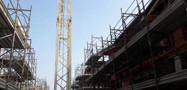 A low angle shot of a construction site with a yellow crane against a blue sky