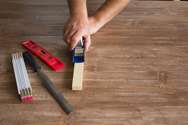 A carpenter\'s hands planning a piece of wood