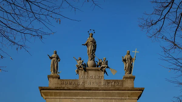 A Low angle shot of a old building with an inscription and sculptures against a blue sky.Tourist attraction