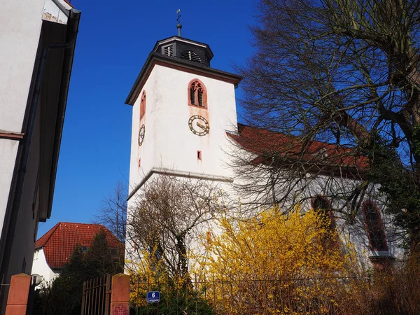 A shot of a white church tower with the clock and black slate roof in Messel Germany