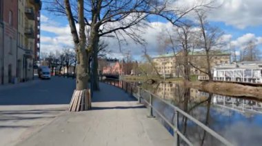 İsveç, Orebro 'daki binaları yansıtan Svartan nehri boyunca yürüyen bir pov.