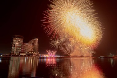 Dubai, Birleşik Arap Emirlikleri 'nde su üzerinde patlayan turuncu havai fişeklerin düşük açılı görüntüsü.