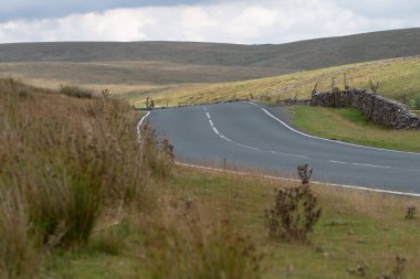 Kırsal bir viraj yolu tarlalardan ve tepelerden geçiyor, bir seyahat konsepti.