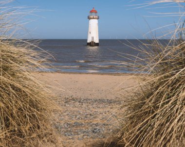 Güneş doğarken Talakre 'nin kumlu sahilinde etkileyici mavi gökyüzü olan deniz fenerinin güzel manzarası.