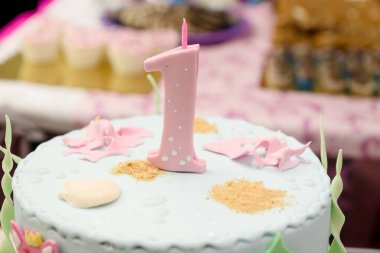 Pembe badem ezmesi bir numara ve ilk doğum günü için küçük bir mum ya da bulanık bir arka planda yıldönümü kutlaması.