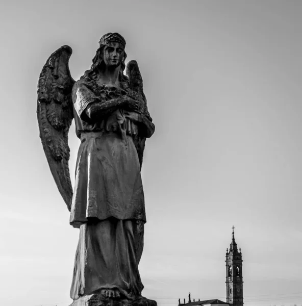 在教堂塔楼的背景下 黑色和白色背景下拍摄的一个天使妇女的低角度雕塑 吸引游客 — 图库照片