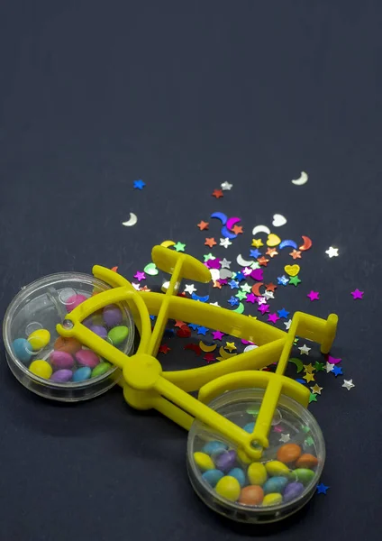 玩具自行车的特写镜头 车轮内装有五彩缤纷的坚果糖 旁边闪烁着亮晶晶的形状 — 图库照片