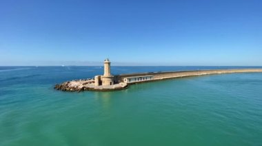 Mavi gökyüzüne karşı denizle çevrili güzel bir deniz feneri manzarası