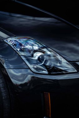 Siyah bir arabanın farının dikey yakın çekimi.