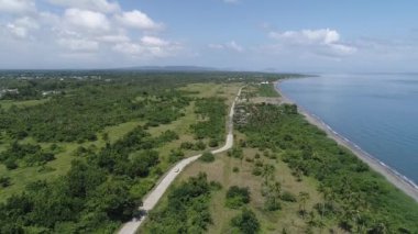 Bir su kütlesinin yakınındaki bir orman arazisinden geçen bir yolun hava görüntüsü.