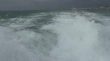 Gri bulutlu gökyüzüne karşı hareket eden bir tekneden denize güzel bir çekim.