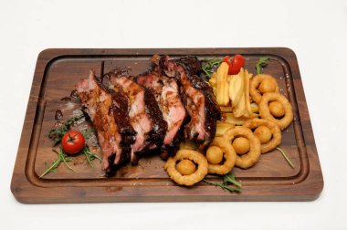 Tahtanın üzerinde soğan halkalarıyla dilimlenmiş leziz etin yakın plan çekimi.