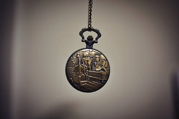A metallic old quartz pocket watch hanged on a clear background