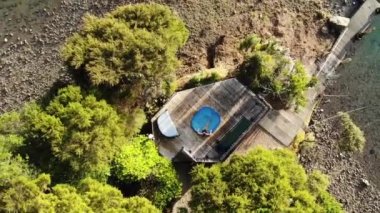 Plajın kıyısındaki küçük bir yüzme havuzunda oturan bir kadının hava görüntüsü.