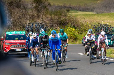 Bir grup bisikletçi Tirreno-Adriatico yol bisiklet yarışında yokuş yukarı seyahat ediyor.