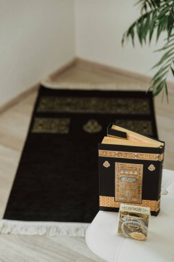 Kabe deseniyle süslenmiş siyah halıyla siyah kadife Kuran ve Ramazan Kareem yazılı tespih.