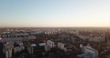 Gün batımında yeşilliklerle çevrili binaların manzarası.