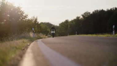 Yolda sarı motosiklet süren bir adam.