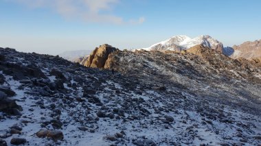 Açık gökyüzünün altındaki kayalık dağların karlı zirveleri