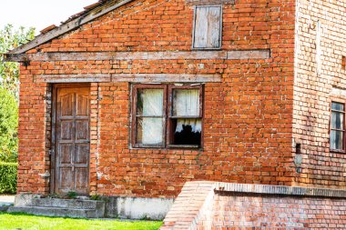 Kırık camları olan eski ve terk edilmiş bir tuğla ev.