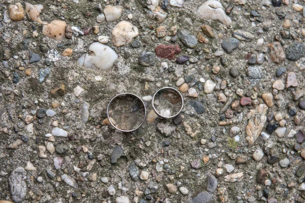 在有纹理的地面上拍了两张结婚戒指的特写 — 图库照片