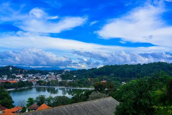 白い雲と緑に囲まれた湖のある村と青い空 — ストック写真