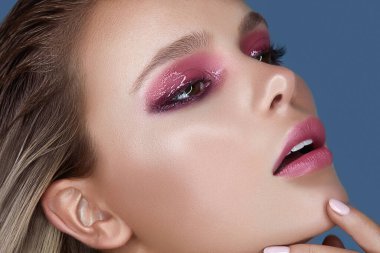 Gri arka planda ıslak makyajlı beyaz bir bayan poz veriyor.