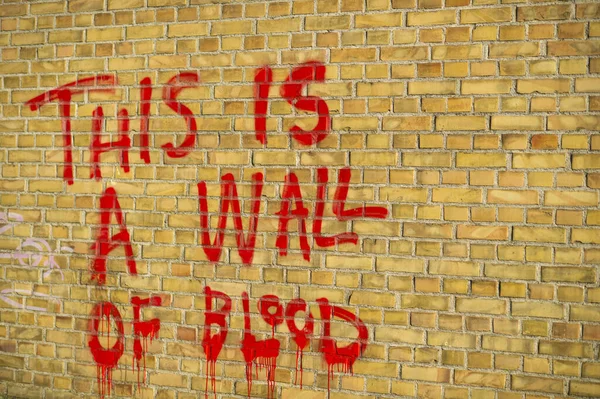 A close-up of a brick wall with text on it - This is a wall of blood