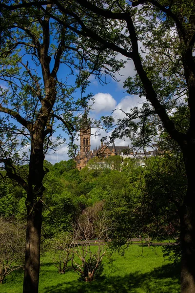 格拉斯哥大学在茂密的绿树后面的一张垂直的照片 — 图库照片