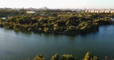 Güneşli bir günde yeşillik ve gölle çevrili güzel bir şehir.