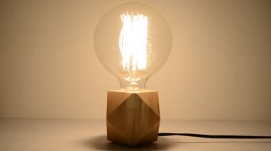 Tungsten ampul lambasını kapat ve koyu arkaplanla bitir. Eski, antika bir ampulün yakın plan görüntüsü ışık saçıyor. Enerji, Elektrik.