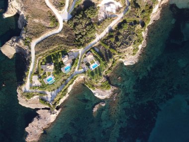 Güneşli bir günde deniz kenarında havuzları olan evler.