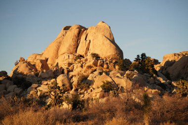 Mavi berrak arkaplan üzerinde küçük kaya parçaları bulunan kaya oluşumları